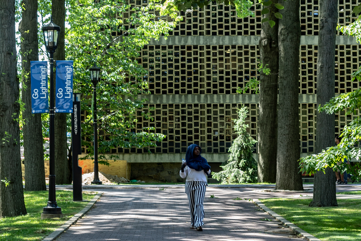 Photo of Shuster building, a student is seen walking
