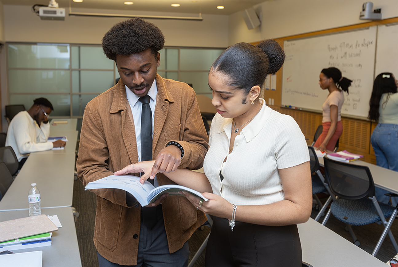 Two students studying together and reviewing course materials in a classroom at Lehman College.