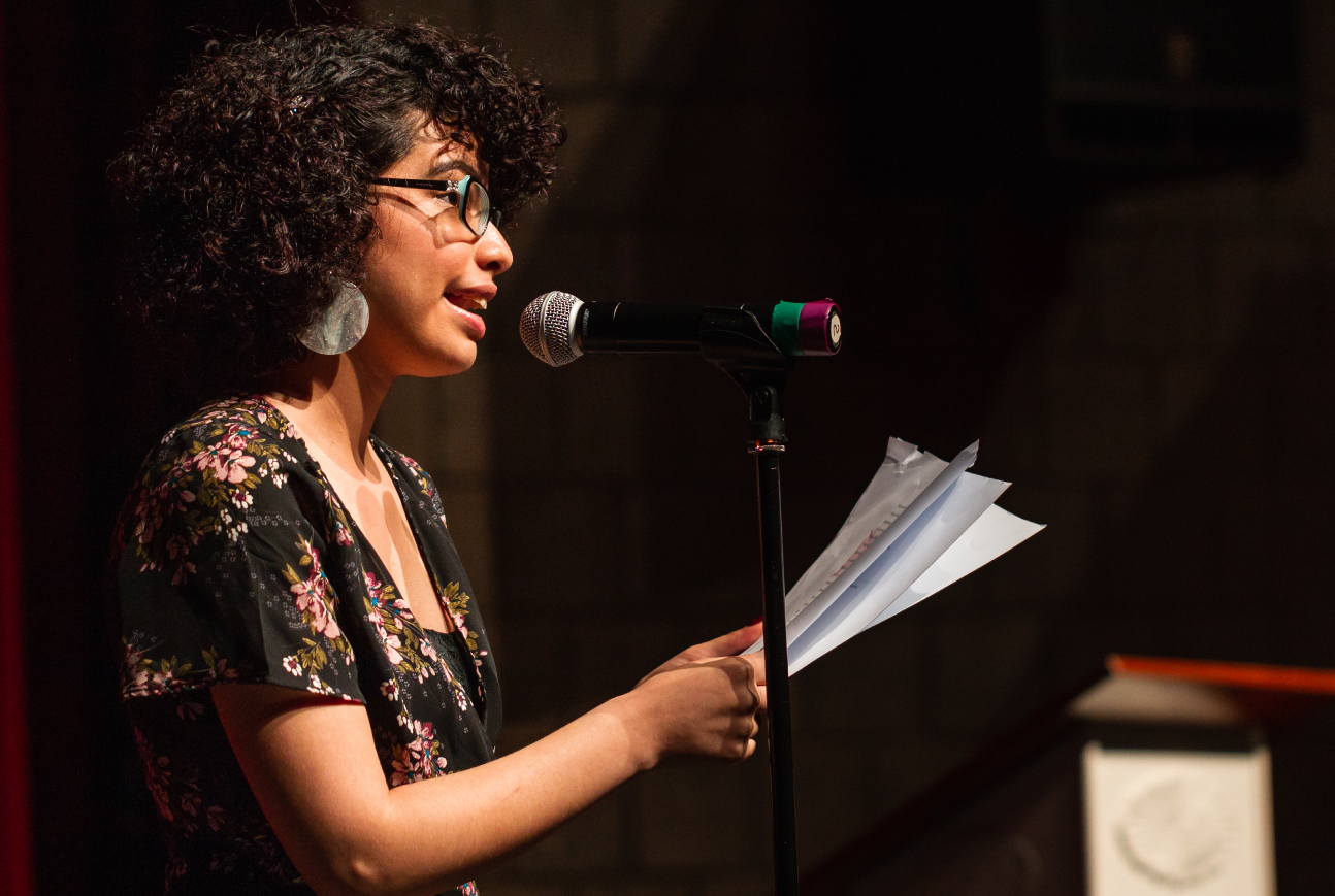 A woman reads her paper to an audience.