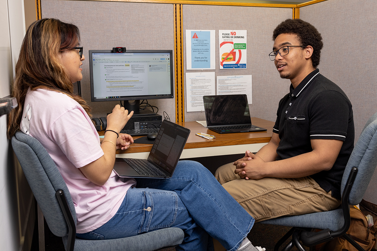 Photo of two students engaging in a conversation while at the tutoring lab