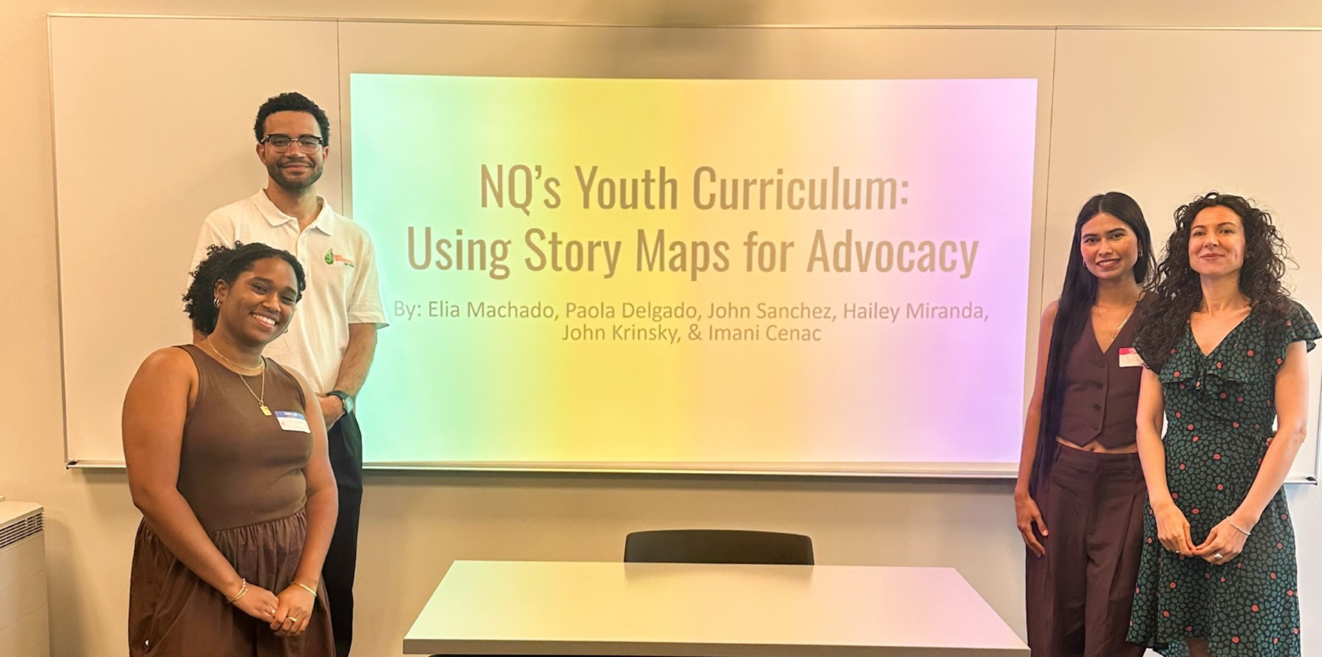 four people standing in front of a presentation slide projected on a screen that reads 