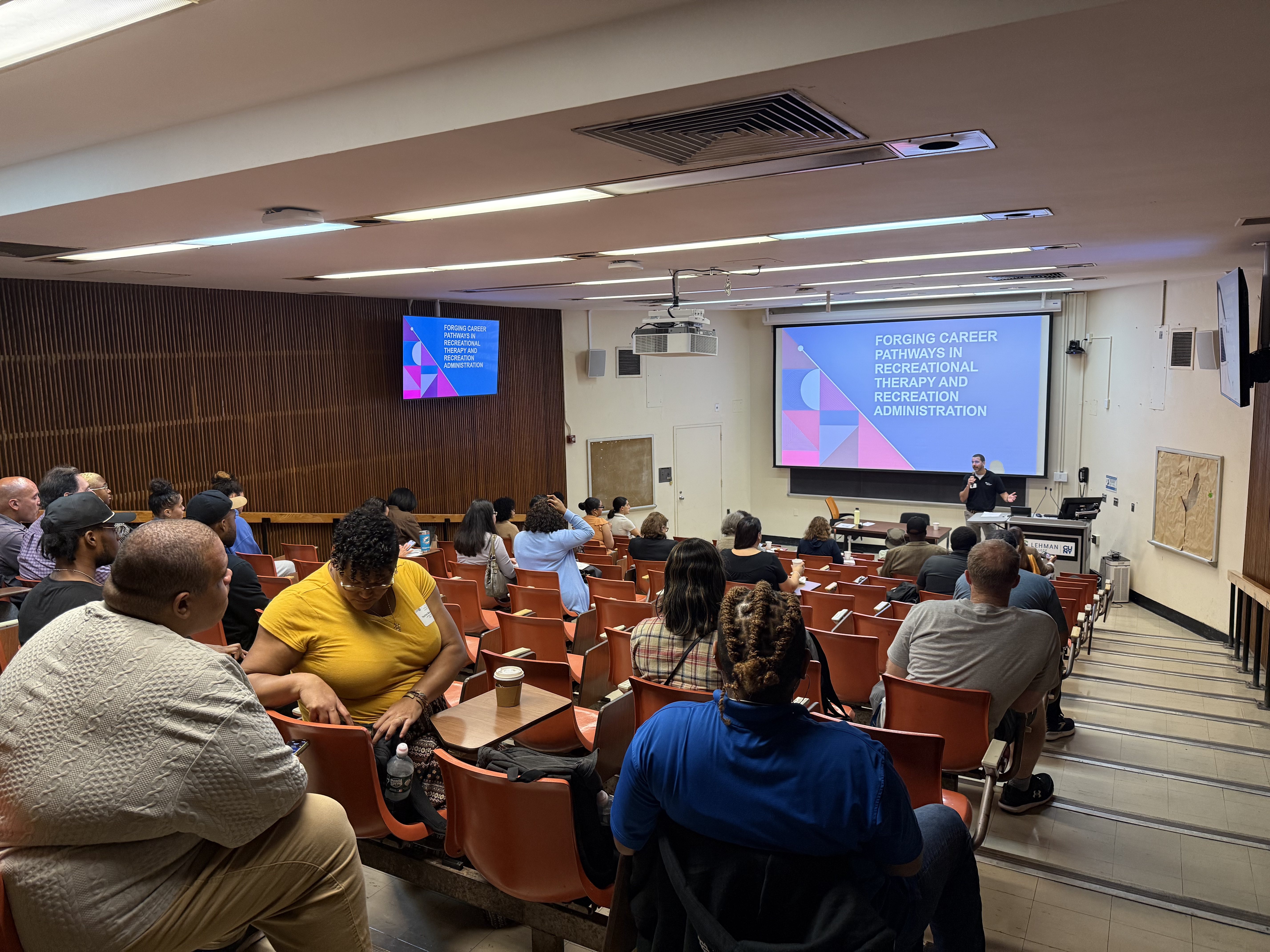 a man giving a slide presentation in a lecture hall.