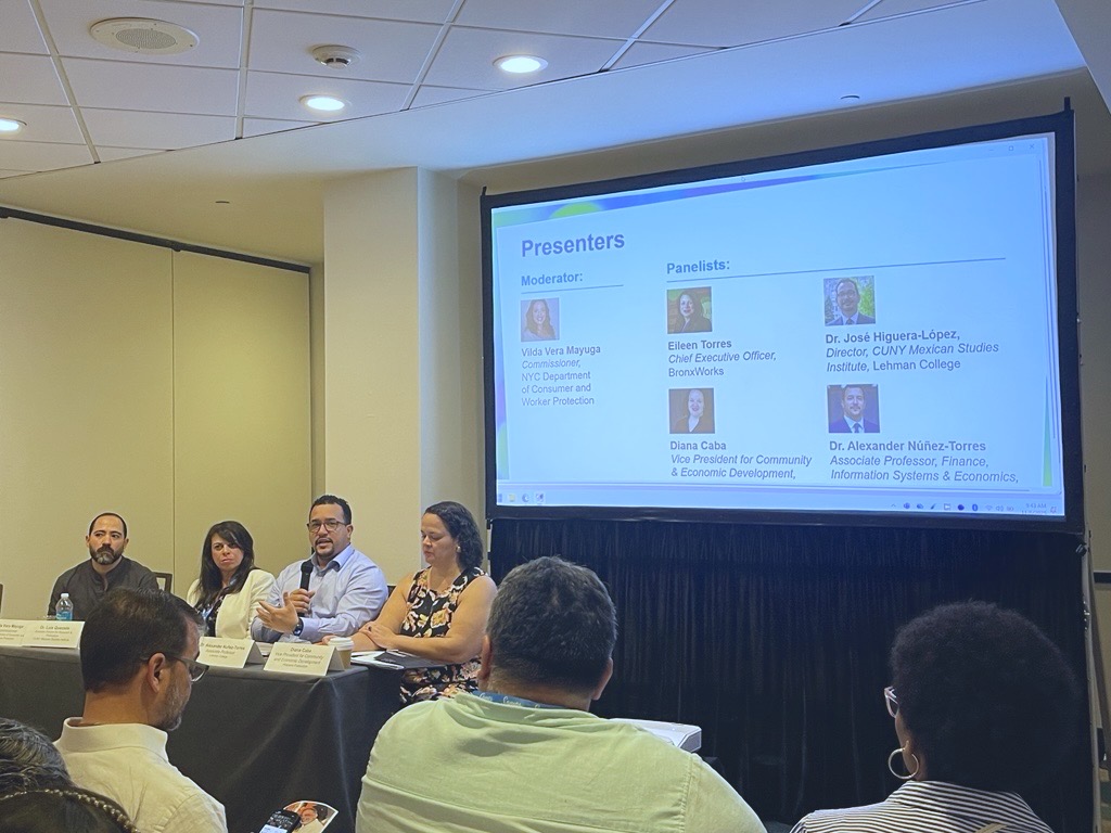 Four people at a table having a panel discussion in front of an audience.